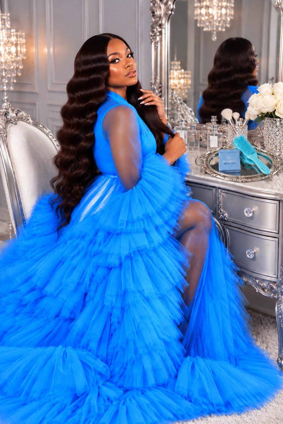 Model with long wavy hair at the vanity beside an Intrigue Beauty box