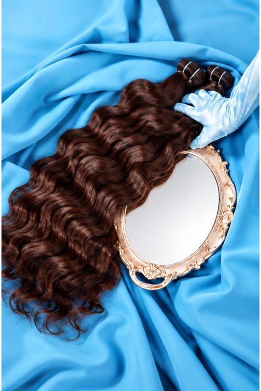 Wavy hair bundles on blue satin with a gold hand mirror