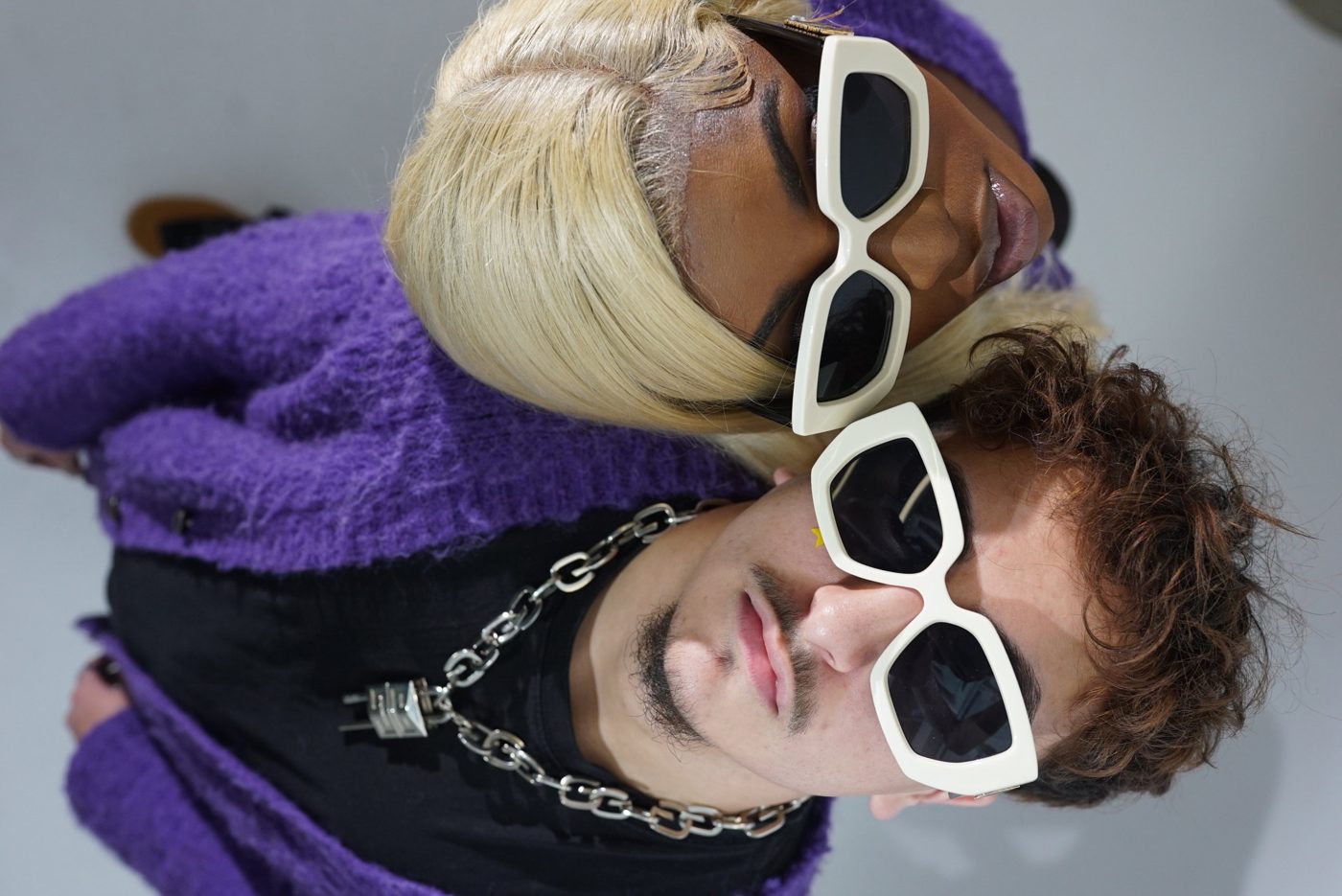 Overhead shot of two models head to head in cream sunglasses and purple cardigans
