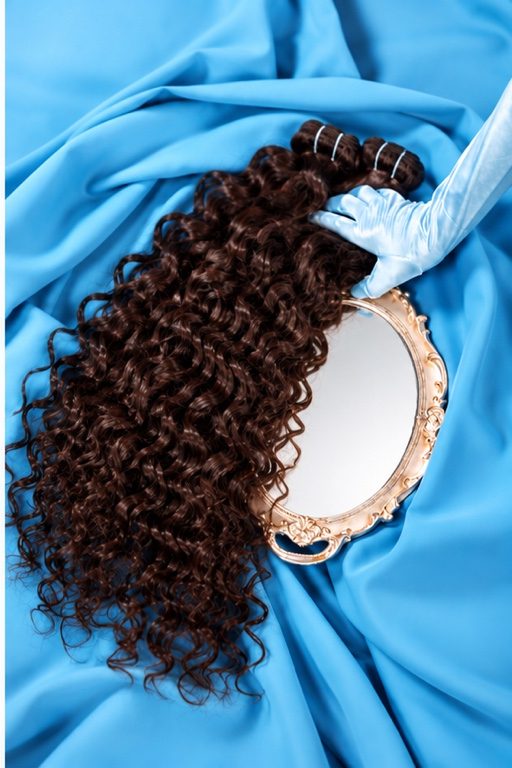 Curly hair bundles on blue satin with a gold hand mirror
