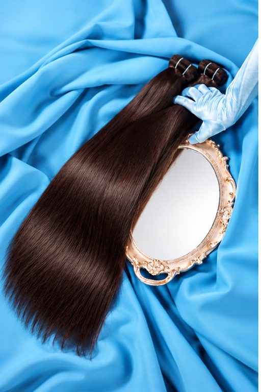 Straight hair bundles on blue satin with a gold hand mirror